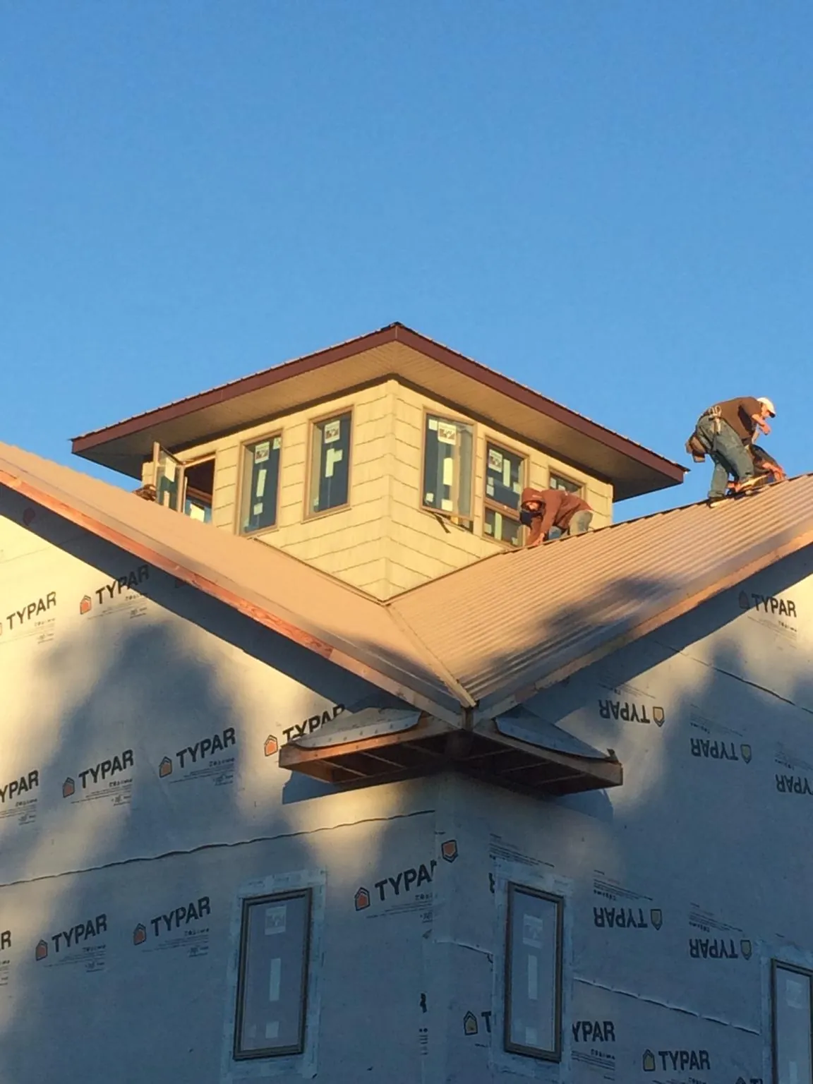 Roofers working around a rooftop cupola on a new metal roof at sunset — Roof Waterproofing in Henry by Roofing Brothers